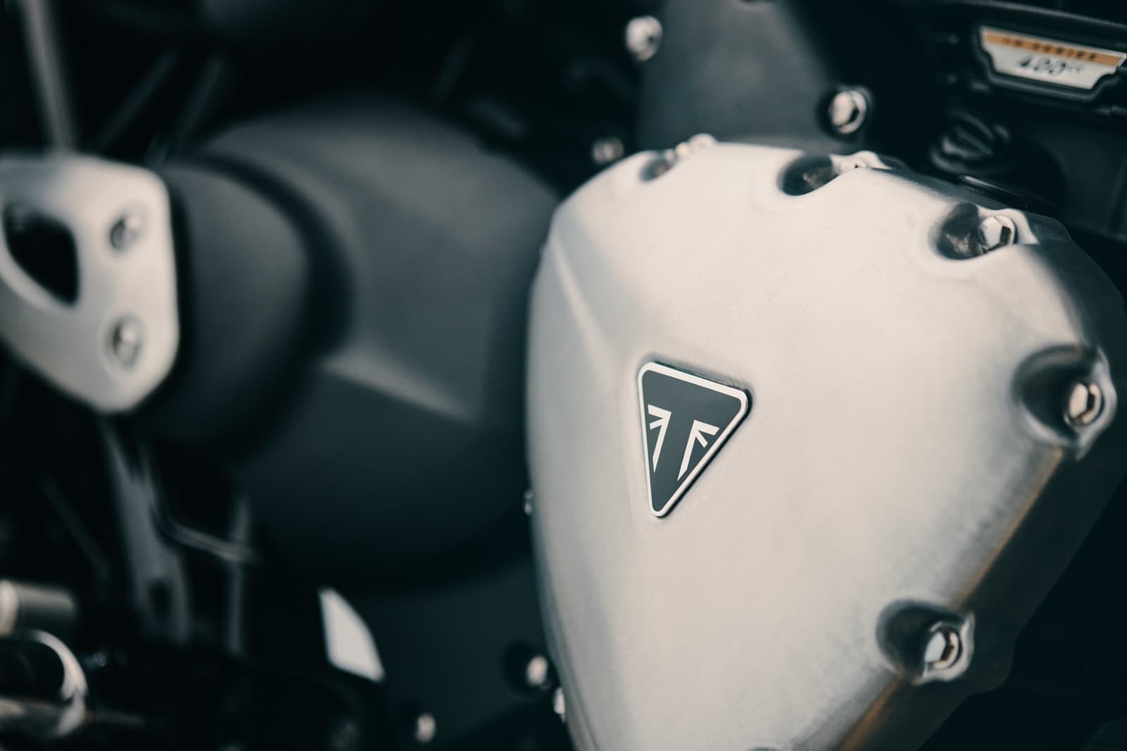 Detalhe da tampa do motor em alumínio escovado da Bonneville T40 com o emblema triangular Triumph
