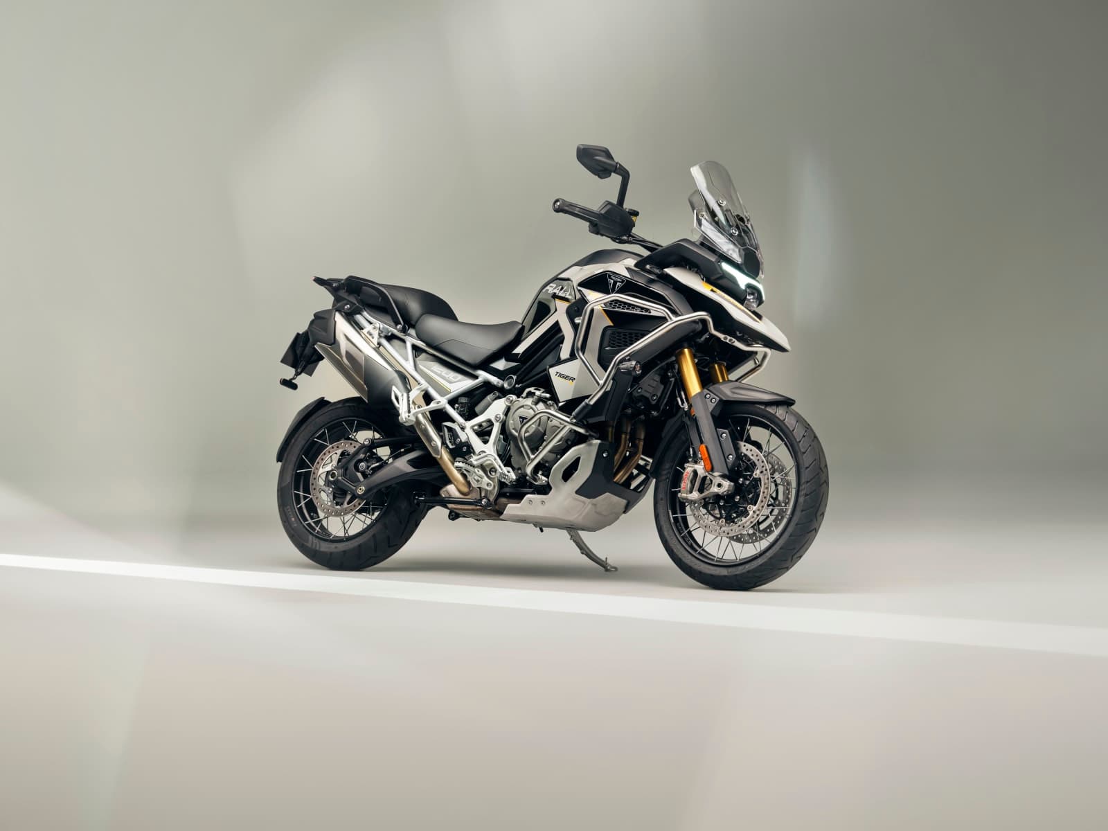 Triumph Tiger 1200 Rally Explorer 2027 branca e preta com suspensão dourada e rodas raiadas
